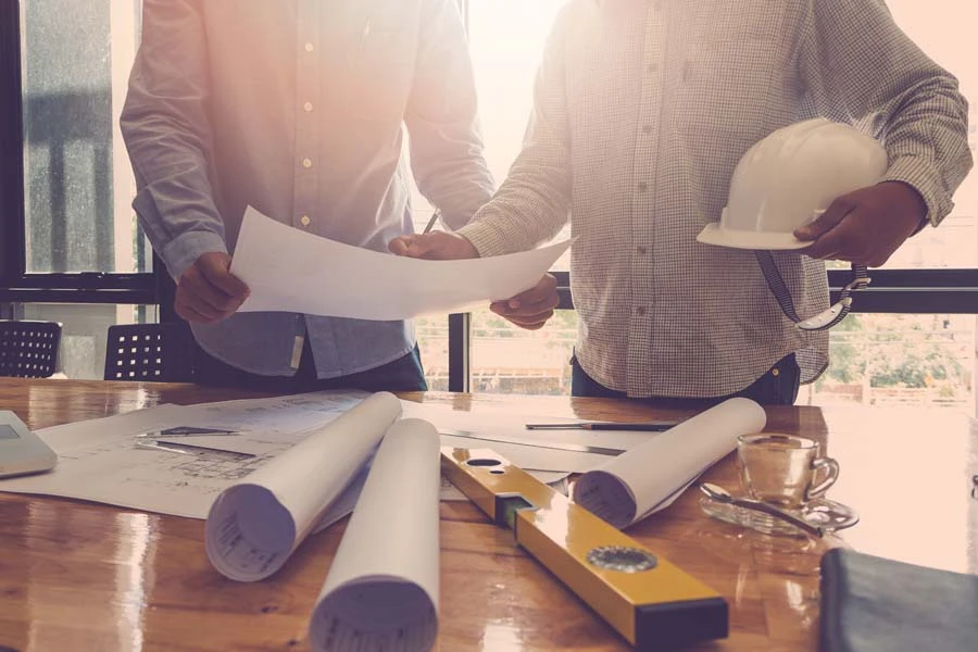 Deux couvreurs professionnels travaillent sur une toiture en chantier au coucher du soleil