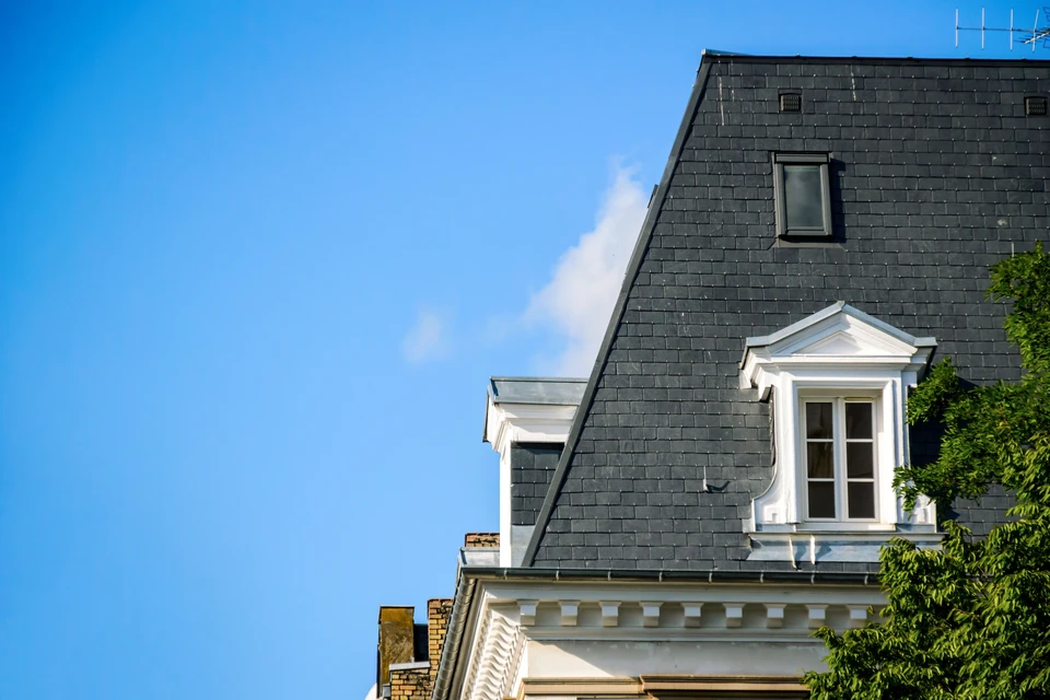 Ouvrier couvreur travaillant sur toiture ardoise d'une maison traditionnelle en pierre