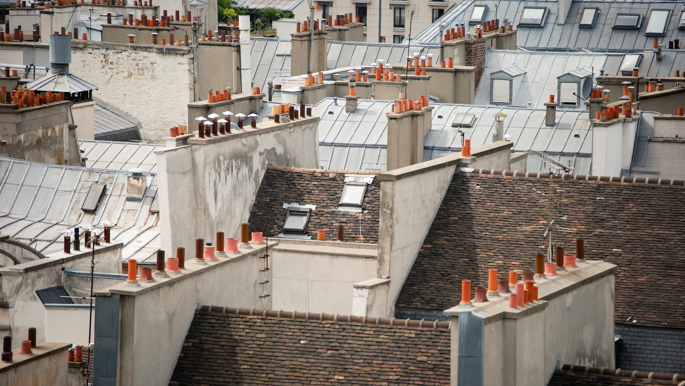 Couvreur installant des tuiles sur une toiture en construction, travaillant à genoux sur des tuiles noires brillantes