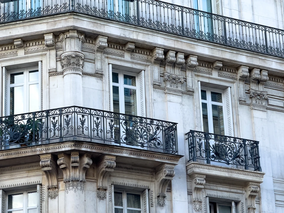 Façades d'immeubles parisiens typiques avec fenêtres à volets en bois, balconnets en fer forgé et lucarnes mansardées