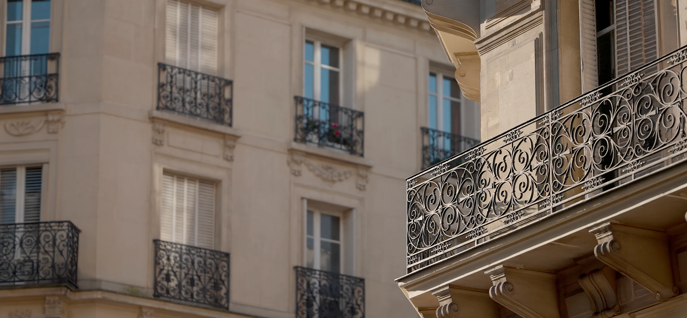 Gros plan professionnel montrant la réfection d'un balcon en plomb haussmannien parisien : balustrade en plomb massif travaillé à la main, structures courbes et décoratives typiques de l'architecture parisienne classique, avec des détails visibles du matériau plomb au premier plan, prise de vue depuis la rue regardant un bel immeuble haussmannien ancien avec ses ornements architecturaux typiques, lumière naturelle mettant en valeur l'artisanat et la qualité du travail de rénovation.