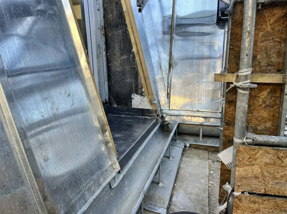 Deux couvreurs professionnels travaillent sur une toiture en chantier au coucher du soleil