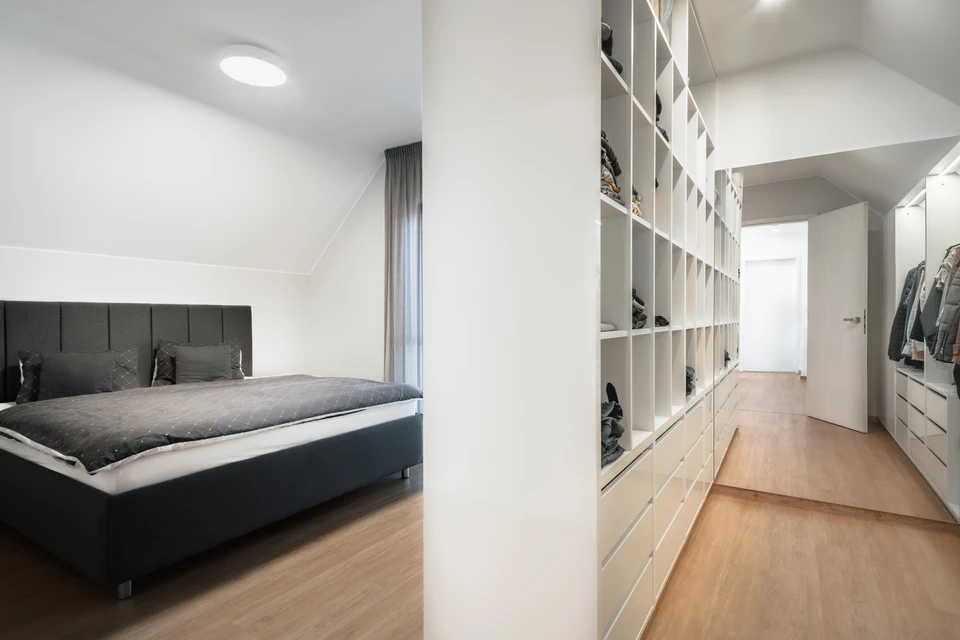 Ouvrier en combinaison bleue installant de l'isolant thermique jaune dans les combles d'une habitation