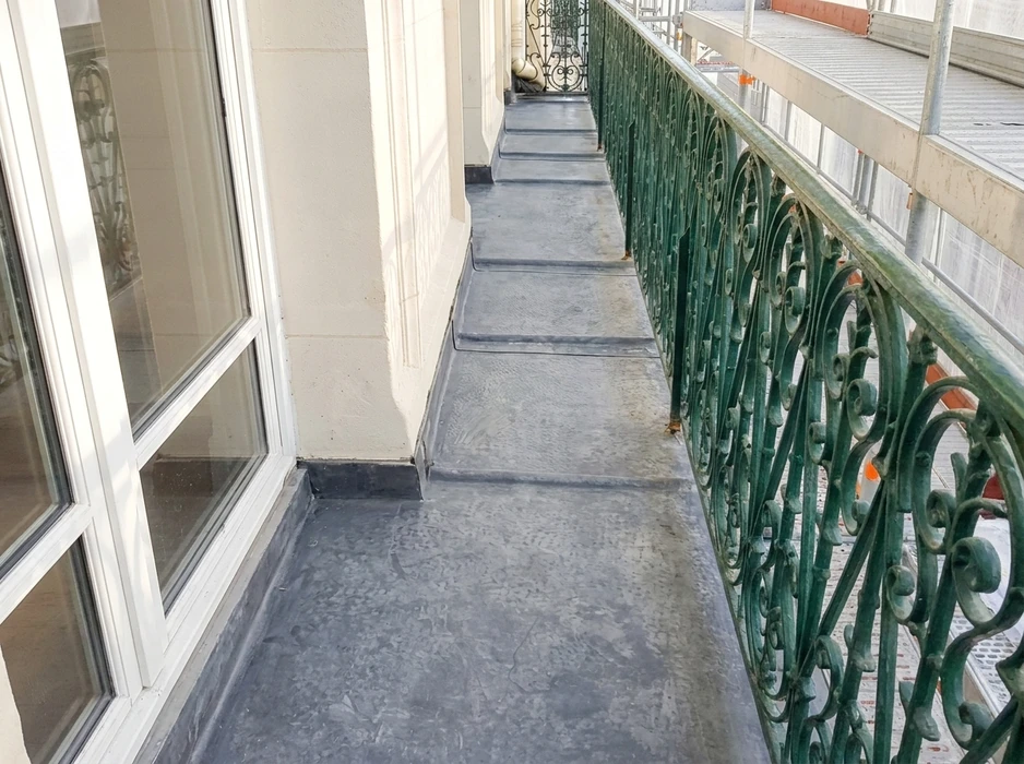 Couvreur professionnel travaillant sur toiture en tuiles métalliques, utilisant une échelle de toit pour accéder à une cheminée en briques